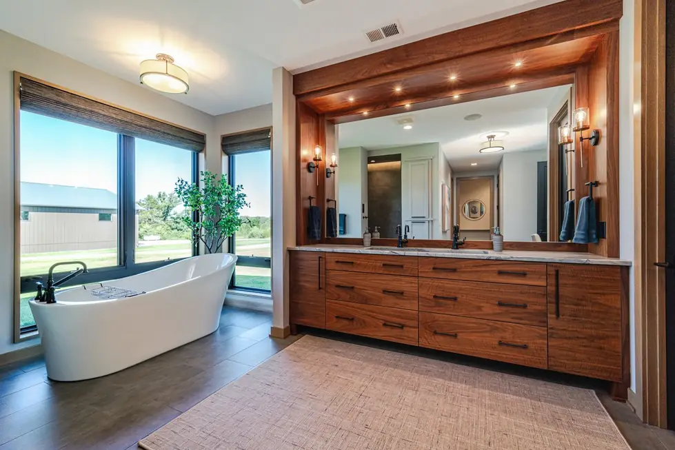 Primary bathroom remodel by Avid Builders with a freestanding tub and a walnut double vanity