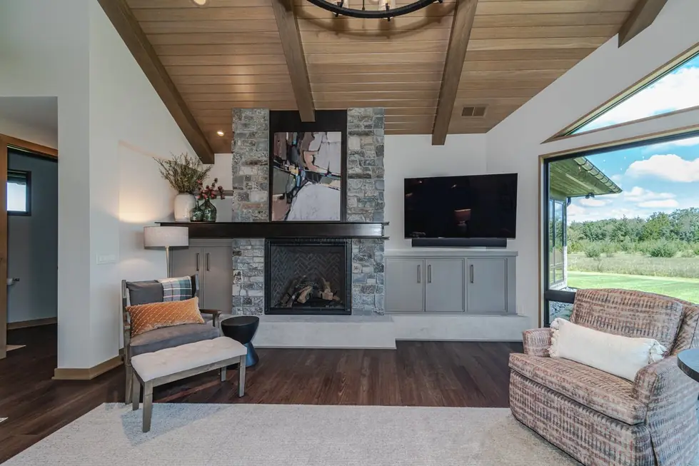Great room remodel with a full-height stone fireplace under an exposed wood beam ceiling